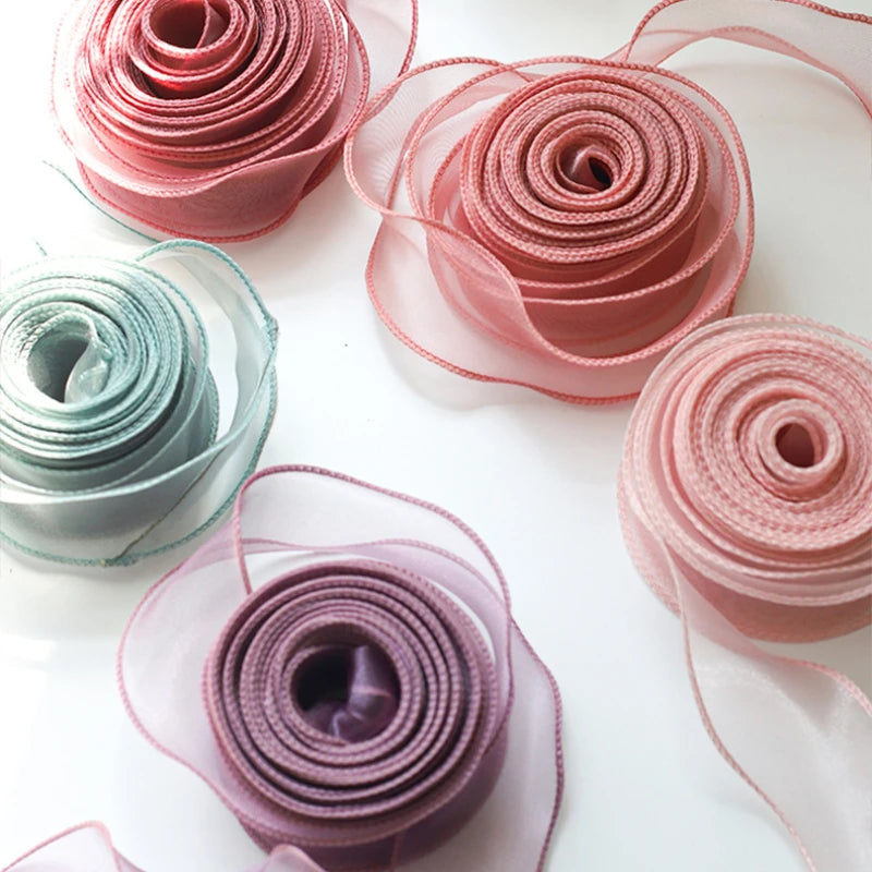 A collection of rolled pink and mauve organza ribbons in various shades and transparencies.