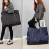 A woman is holding a dark gray reusable large-capacity grocery tote bag.