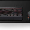 A black mechanical keyboard and an orange gaming mouse are displayed on a black desk mat.