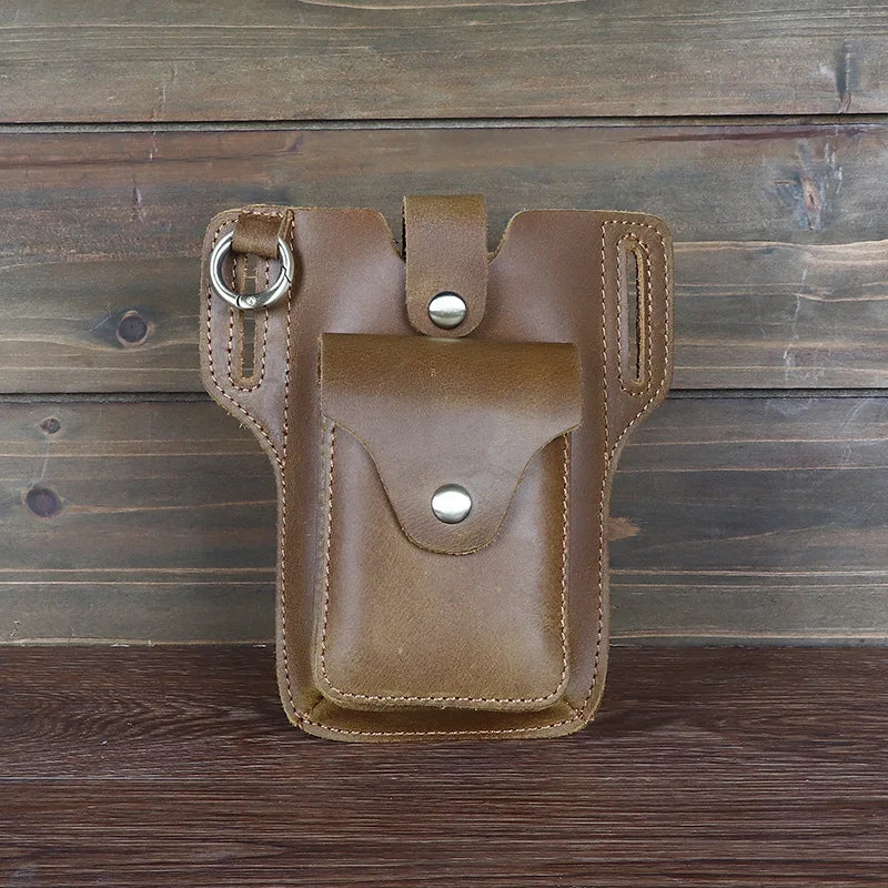 A brown genuine leather waist bag with a flap and buckle is displayed on a dark wooden surface.