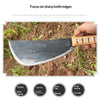A hand holds a black forged steel knife blade resting on dirt, demonstrating sharp edges and durability.