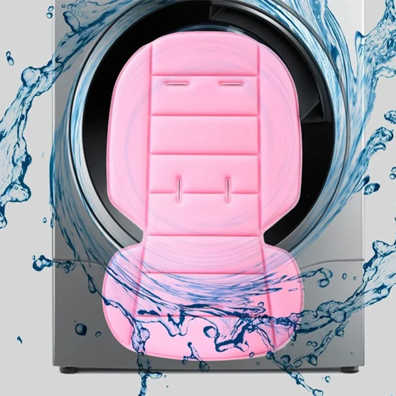 A pink cartoon baby stroller seat cushion is shown inside a washing machine drum surrounded by splashing water.