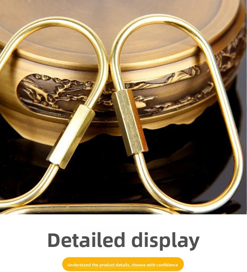 A set of gold brass keychain charms with locking carabiner clips displayed on a dark surface.