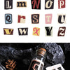 A collection of vintage alphabet stickers arranged in a grid, with a glass bottle featuring the letter S and a separate U sti