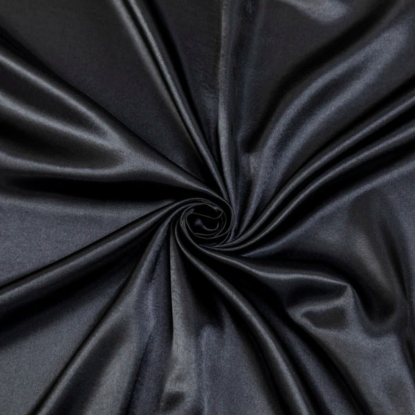 A dark gray satin bed sheet set with pillowcases gathered into a swirl.