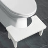 A white bamboo toilet squat stool with a seat and legs is shown on a gray tiled floor.