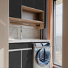 A modern bathroom vanity featuring a white countertop, sink, and a built-in washing machine visible next to a dark gray cabin