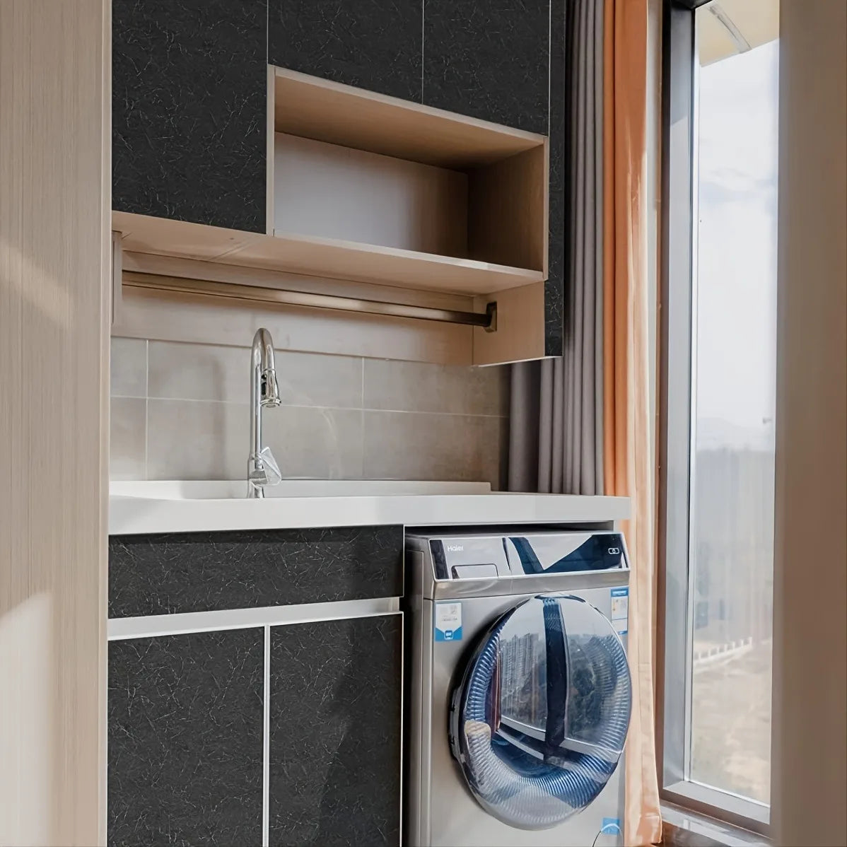 A modern bathroom vanity featuring a white countertop, sink, and a built-in washing machine visible next to a dark gray cabin