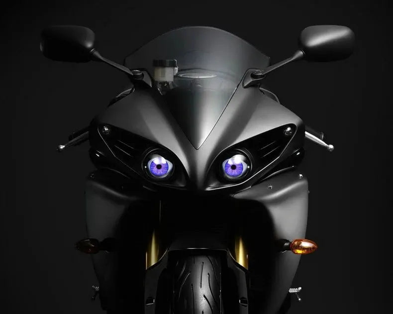 A close-up view of a black motorcycle headlight with blue LED eyes and remote control features.