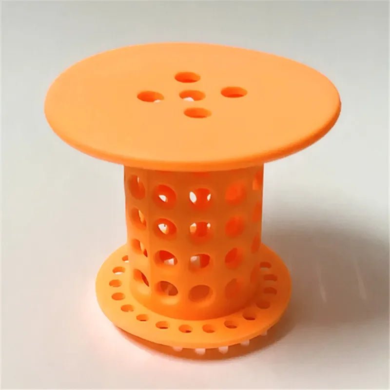 An orange flexible hair catcher drain cover for sinks and tubs with a perforated top and base.