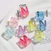 A collection of clear and colored acrylic letter beads spelling the letter N arranged on a white plate.