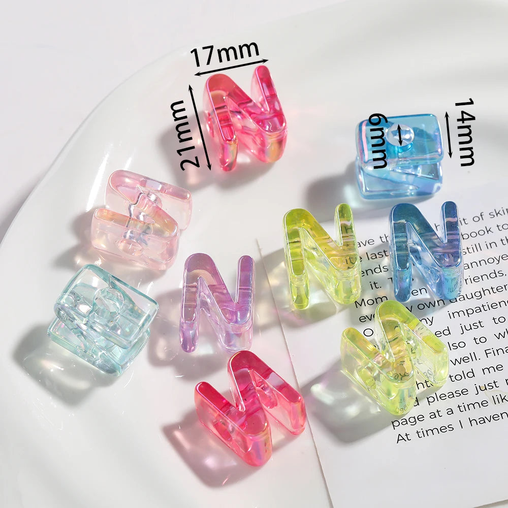 A collection of clear and colored acrylic letter beads spelling the letter N arranged on a white plate.