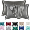 Un juego de fundas de almohada de seda satinada en varios tonos, incluyendo coral, gris y azul.