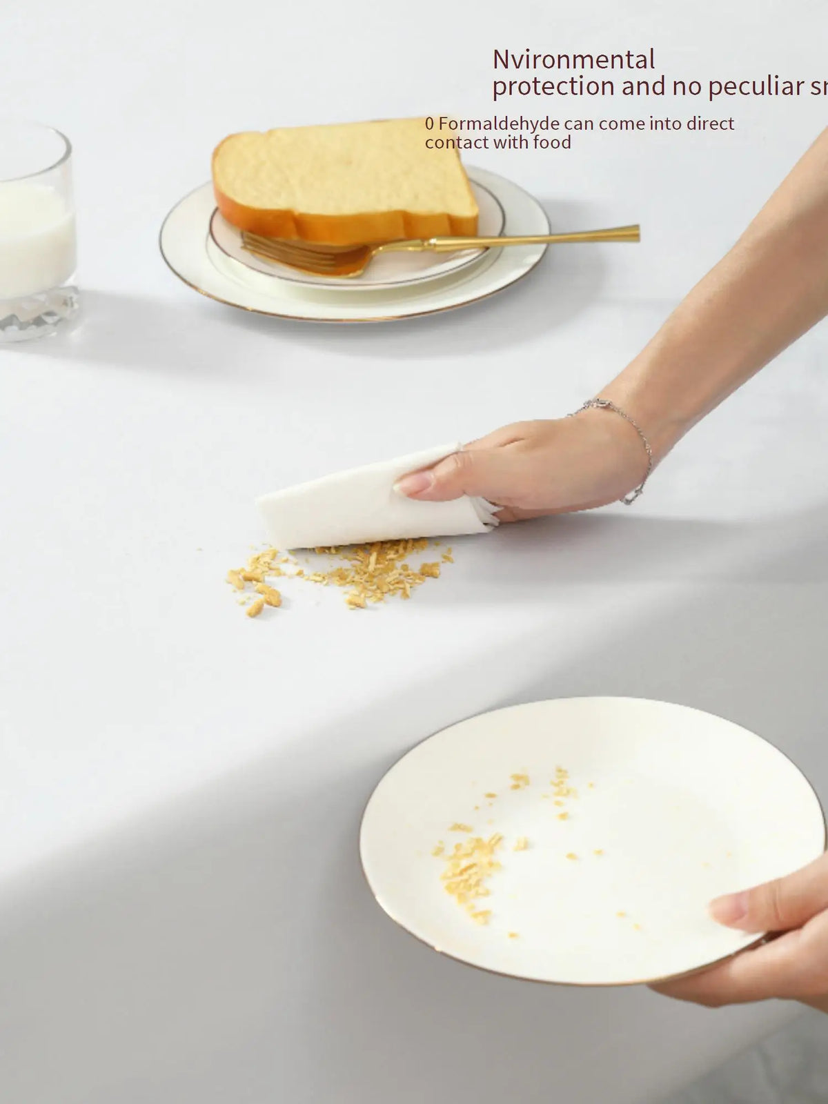A hand is using a white cloth to wipe food residue from a plate on a table.