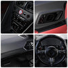Close-up view of a car interior showing carbon fiber trim, dashboard controls, and steering wheel details.