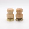 Two wooden dish scrub brushes with natural sisal bristles resting on a white background.