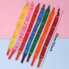 A collection of 10 colored whistling flying party balloons arranged diagonally on a pink and blue background.