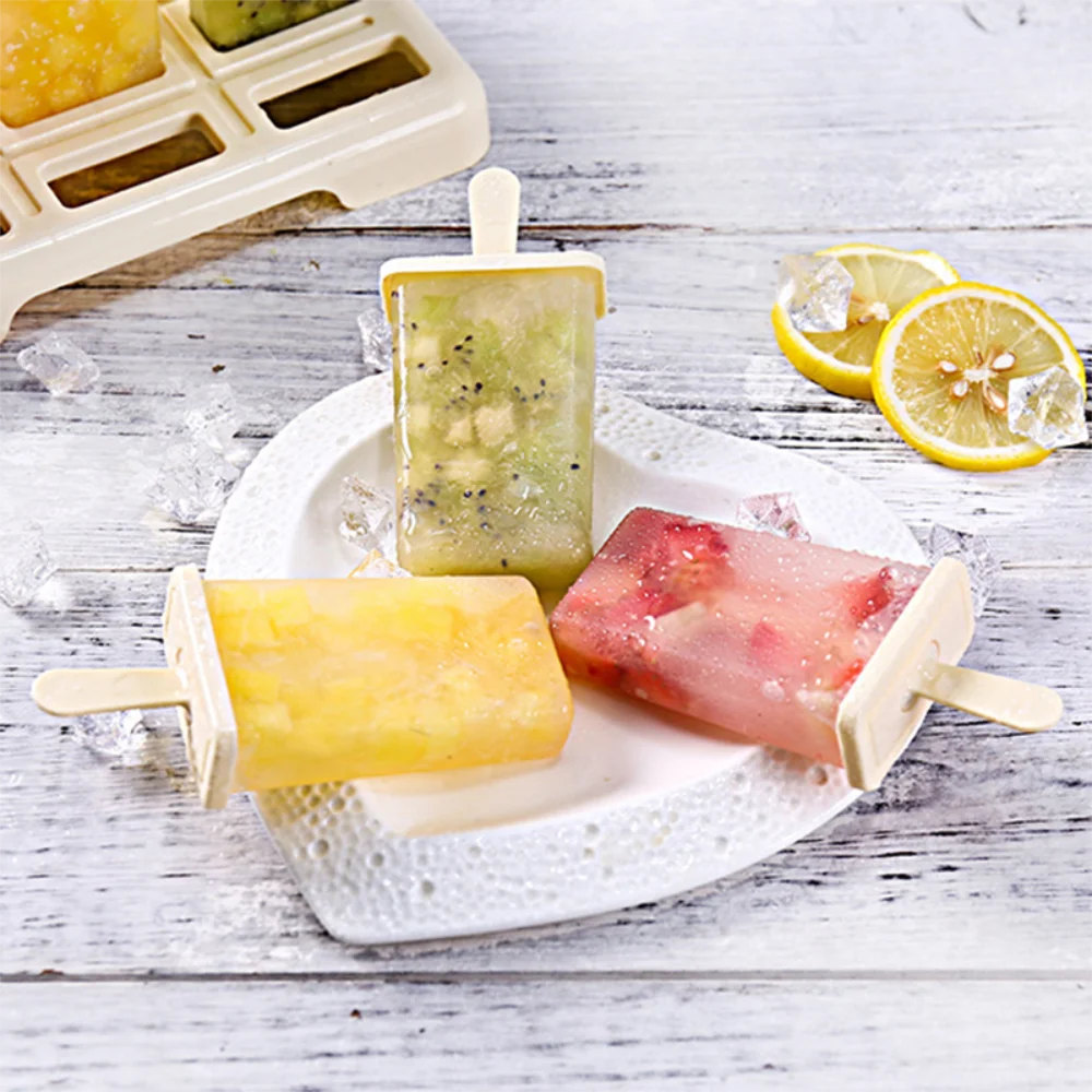 A set of DIY ice cream popsicle molds featuring yellow and green flavored popsicles on a white plate.