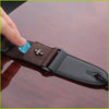 A dark brown guitar strap with a vintage cross pattern and a black pick pocket is shown being held by a hand.