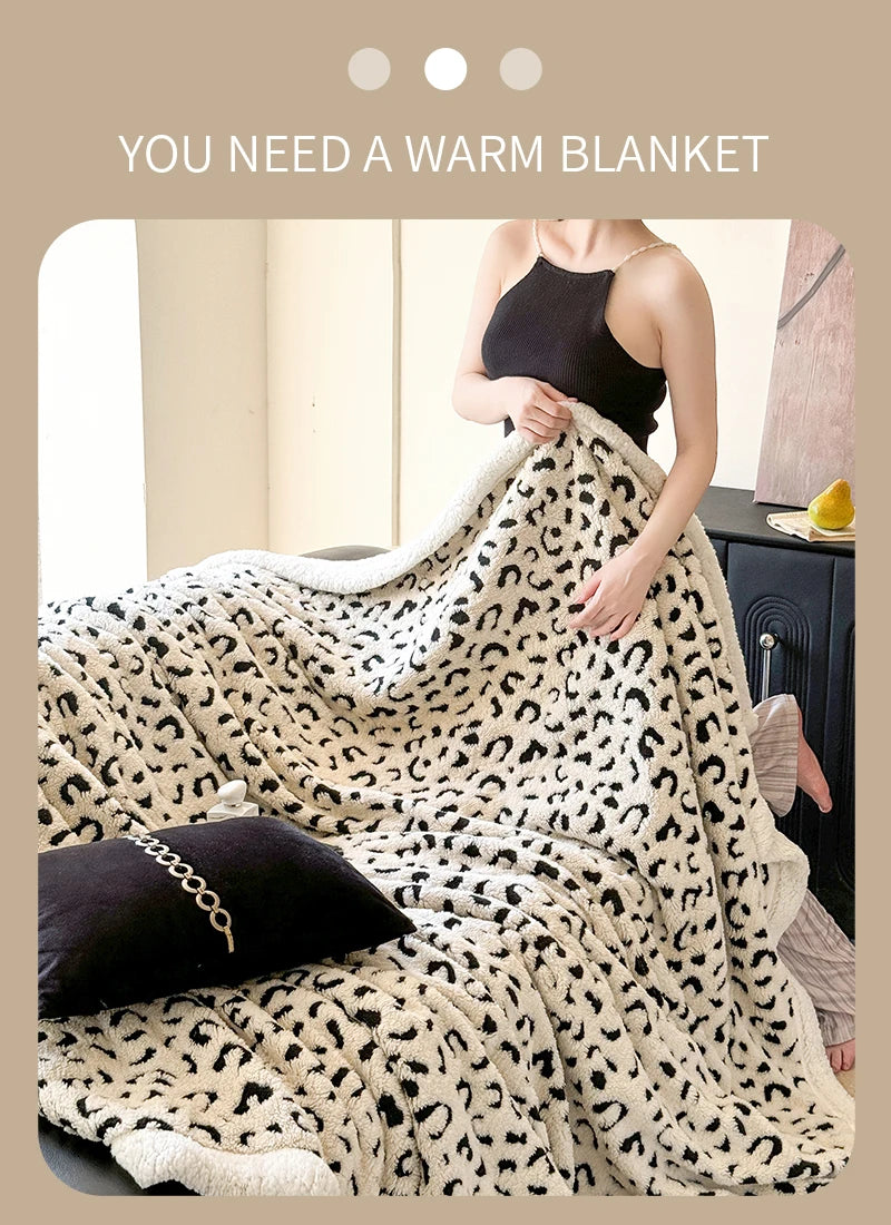 A woman is wrapped in a fluffy leopard print throw blanket indoors.
