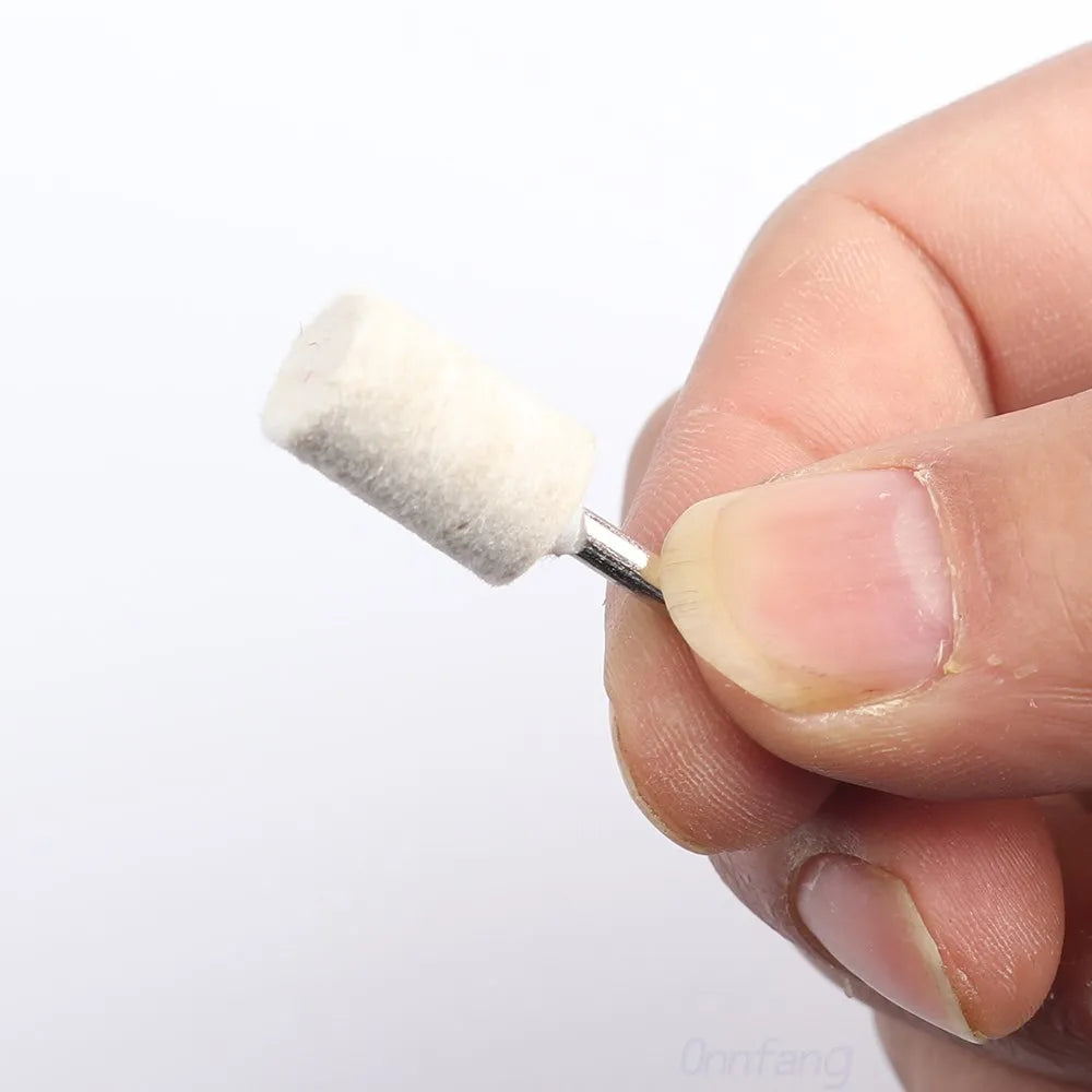 A hand holds a white wool felt polishing wheel with a metal shank for rotary tools.