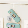 A pair of light green child safety cabinet locks mounted on a white cabinet door.