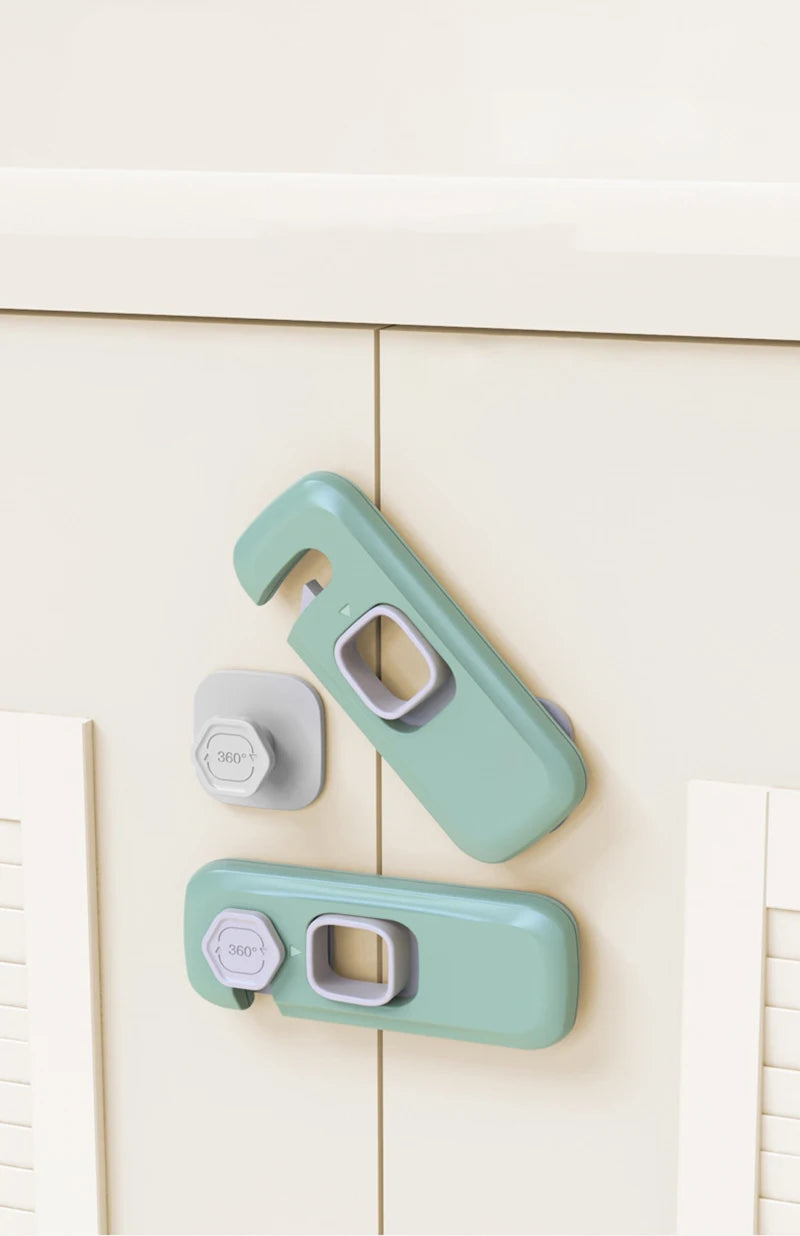 A pair of light green child safety cabinet locks mounted on a white cabinet door.