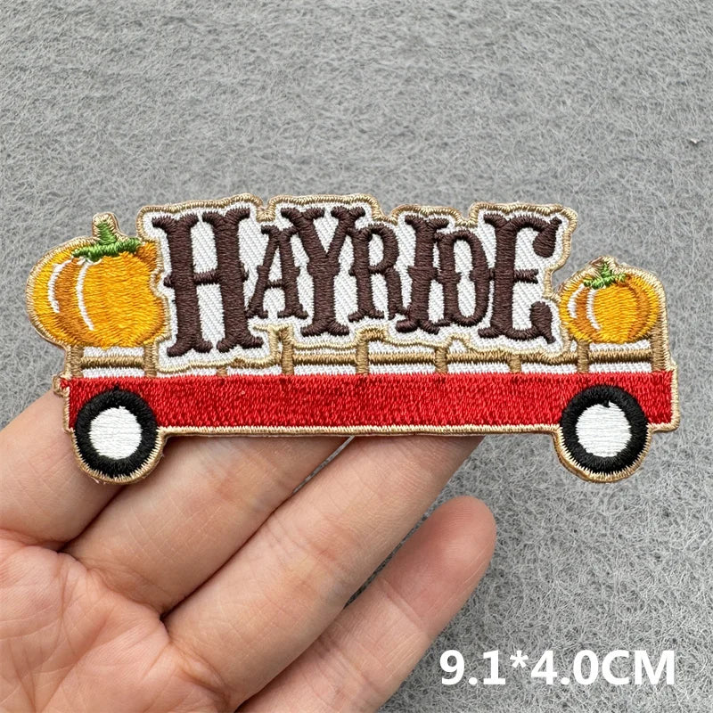 Embroidered iron-on patch featuring the text HAYRIDE on a vintage orange vehicle design