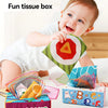 A baby is shown interacting with a fun tissue box filled with colorful cloth book rings and toys.