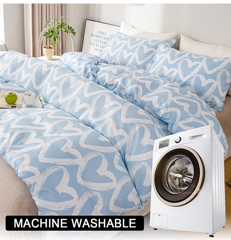 A light blue duvet cover set with a white heart print and matching pillowcases is displayed next to a white washing machine.