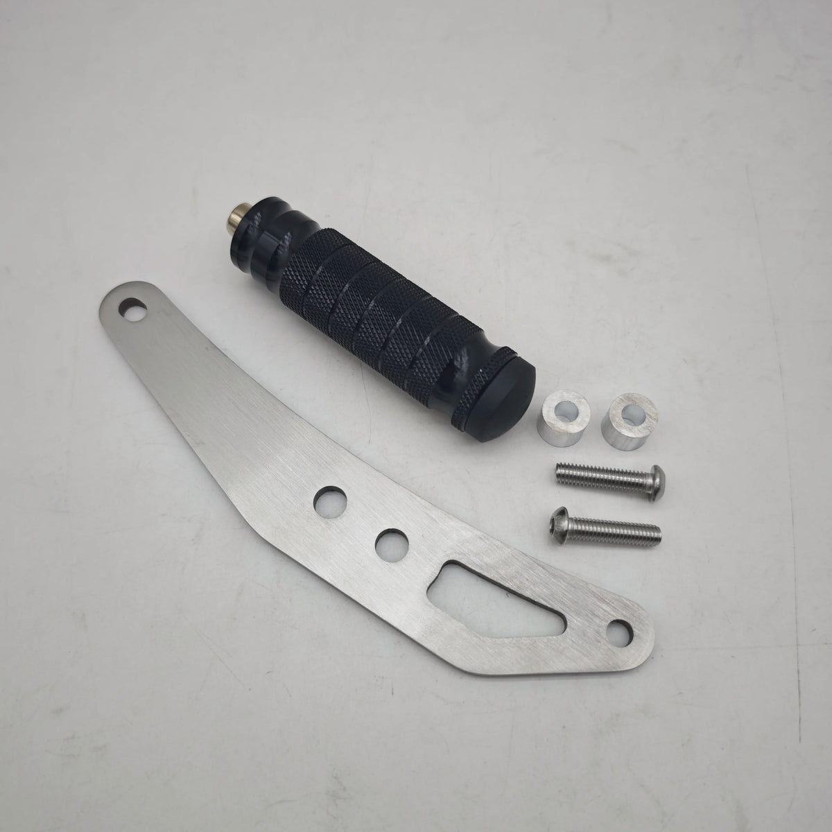 A set of CNC aluminum foot pegs, a black shock absorber, and several screws are displayed on a white background.