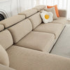 A beige jacquard elastic sofa slipcover with orange accent pillows in a bright living room setting.
