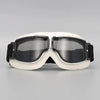 A pair of white retro foldable motorcycle goggles with dark tinted lenses and a black strap.