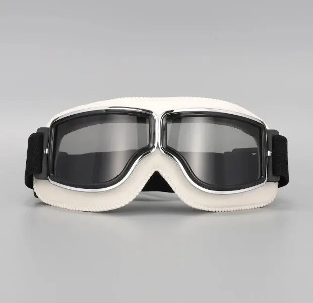 A pair of white retro foldable motorcycle goggles with dark tinted lenses and a black strap.