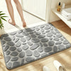 A gray plush non-slip absorbent bathroom rug with a pebble texture placed on a wooden floor.