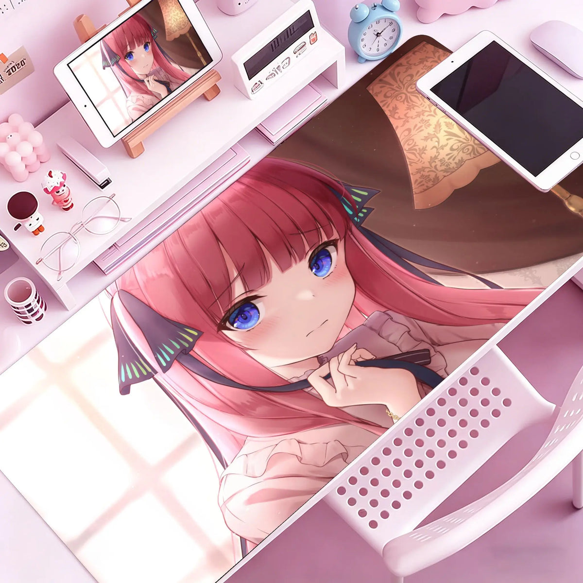 A close-up of a pink-haired anime girl illustration on a mouse pad or desk mat, surrounded by electronic accessories.