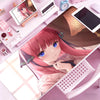 A close-up of a pink-haired anime girl illustration on a mouse pad or desk mat, surrounded by electronic accessories.
