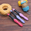 A set of nine interchangeable rechargeable LED crochet hooks in various colors and a spool of yellow paper ribbon on a wooden