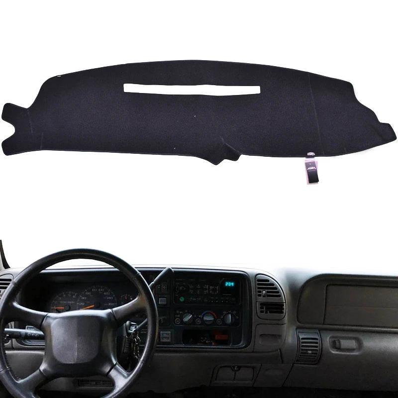Black custom-fit dashboard cover for a truck or SUV shown resting on a steering wheel.