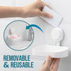 A hand is removing a white suction cup soap dish holder with a removable tray from a tiled surface.