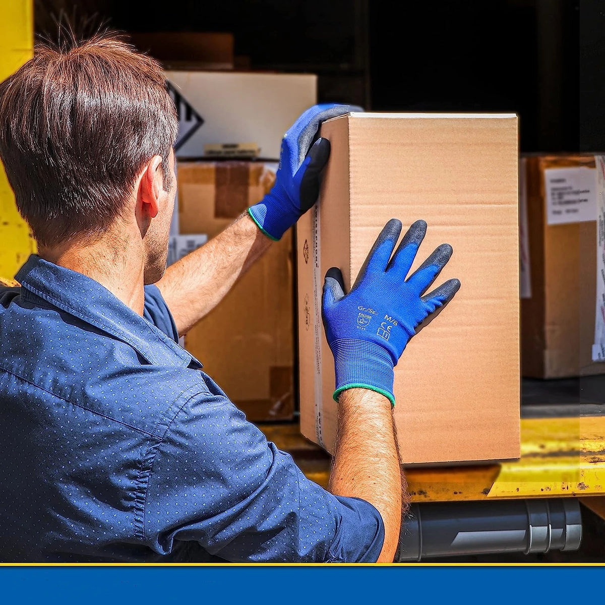 A man wearing blue work gloves is handling a cardboard box with a light brown background.