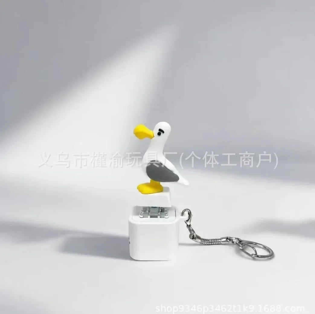 A white seagull figurine keychain fidget toy with an LED light attached to a silver chain.