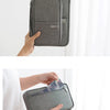 A gray waterproof family passport and document organizer wallet being held by a hand.