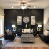 A modern living room featuring a dark accent wall with a large clock and decorative lamps.