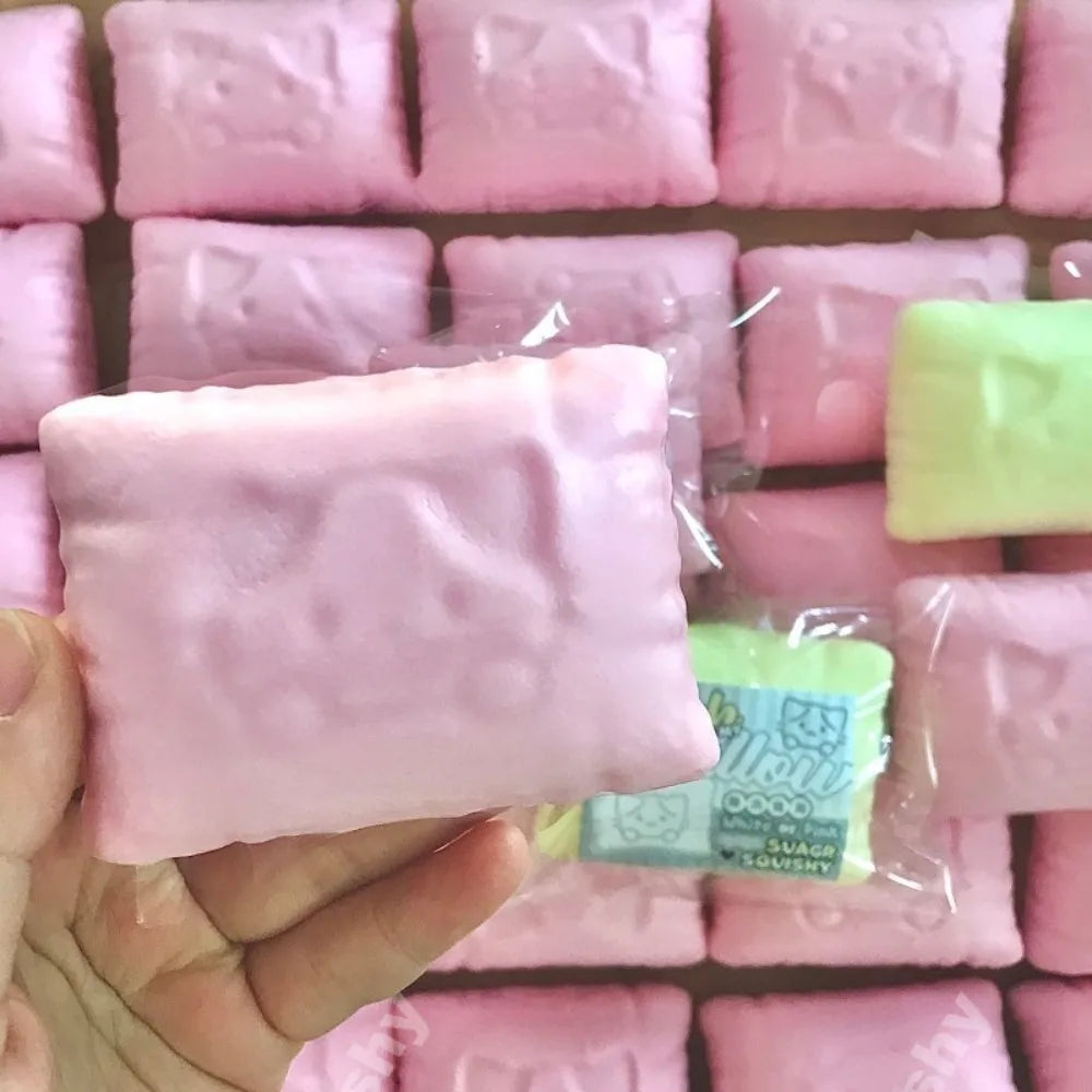 Une main tient un oreiller anti-stress en forme de chat rose, emballé dans du plastique transparent.