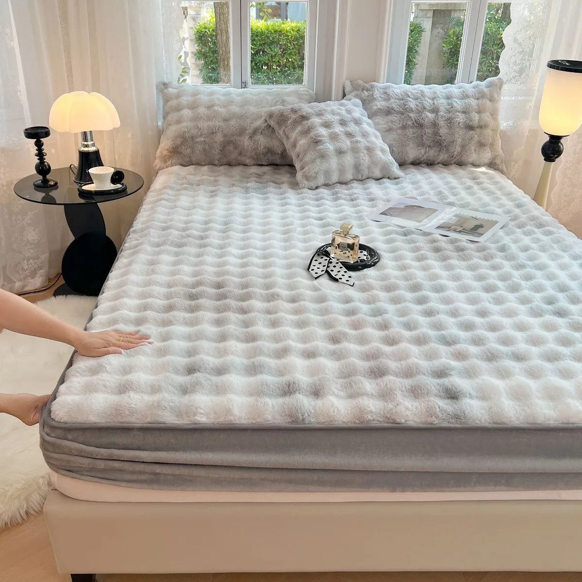 A luxury faux fur fitted sheet and pillowcase set displayed on a bed with light gray bedding and decorative pillows.