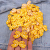 A hand holds a cluster of yellow and white embroidered cartoon bow iron-on patches for DIY clothing decoration.