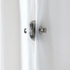 Close-up of a white curtain with a silver magnetic clip and button fastener on the fabric.