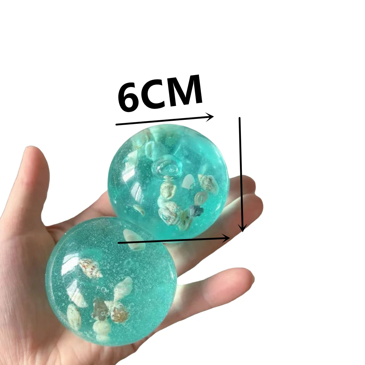 A hand holds a translucent teal ocean squishy stress ball, measuring 6cm in diameter.