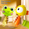 A hand is holding a yellow cartoon animal rattle toy with a green frog head and orange body.
